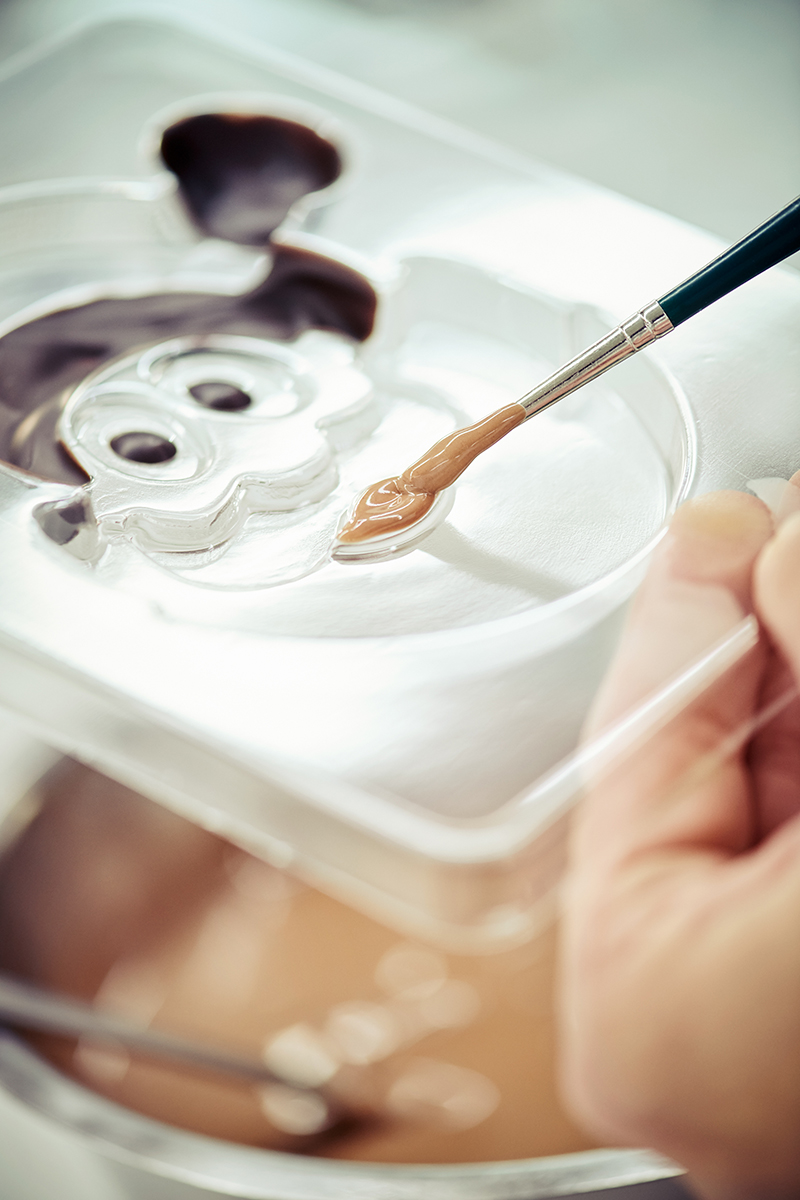 Eine Form für einen Schokoladen Weihnachtsmann wird mit Schokolade bemalt